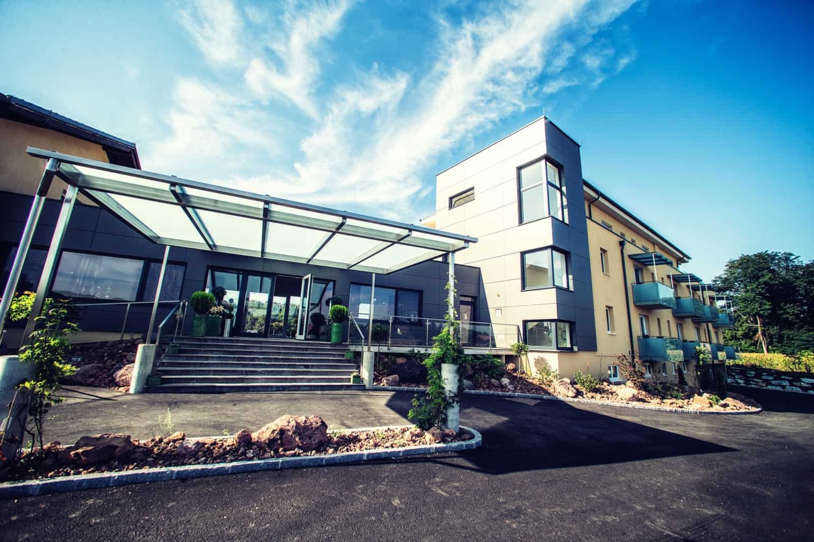 Contemporary hotel building with outdoor terrace and clear blue sky.