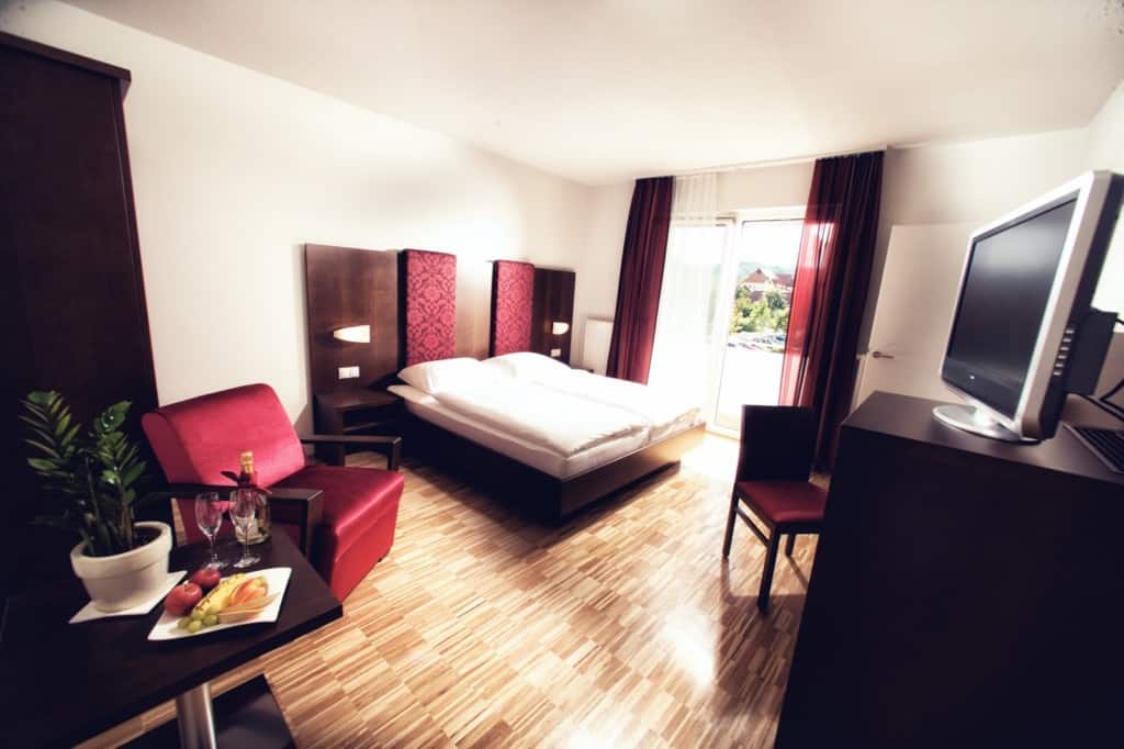 Bright hotel room with comfortable bed, seating area, and scenic view.