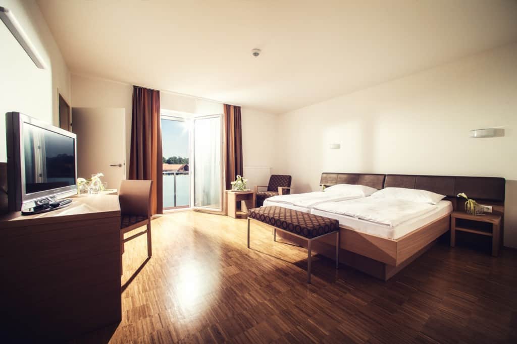 Bright hotel room with a large bed, balcony, and modern amenities.