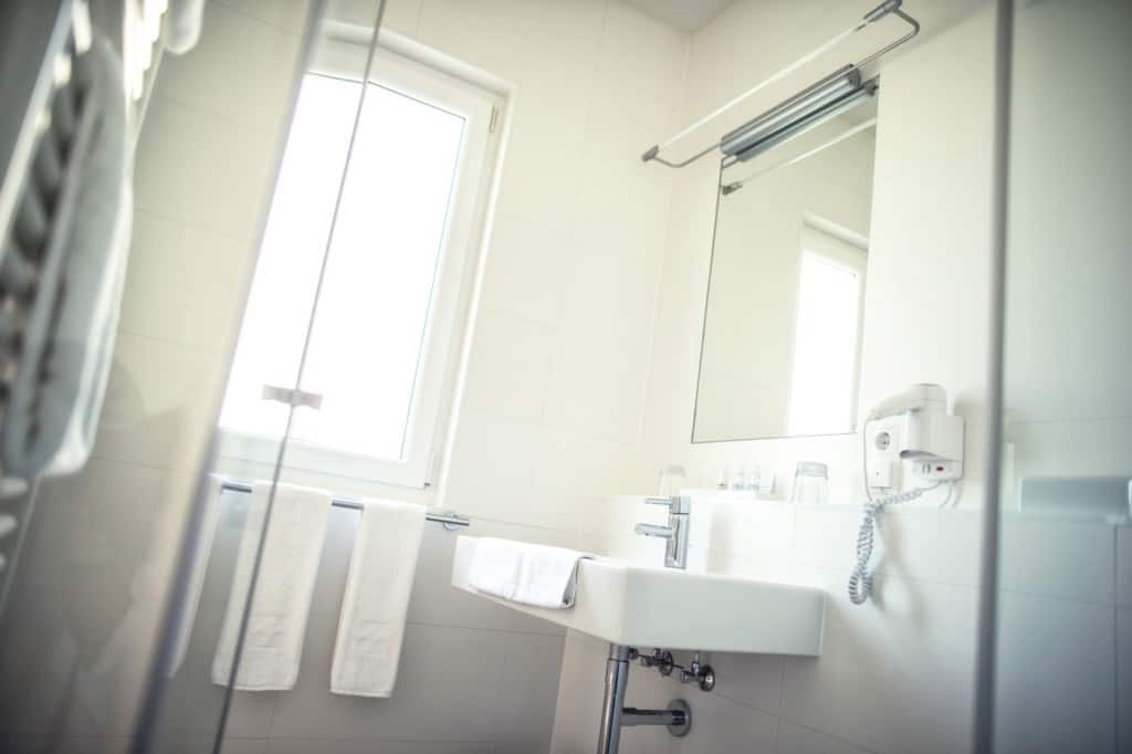 Bright hotel bathroom with large window, clean sink, and towels, offering comfort and relaxation.