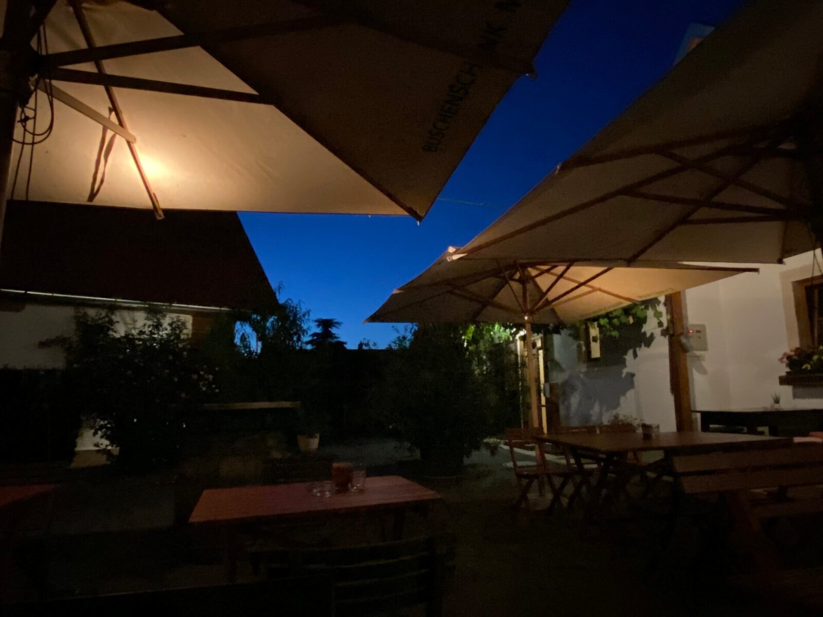 Innenhof mit Tischen und Sonnenschirmen im Abendlicht, ideal für Buschenschank Martinecz.