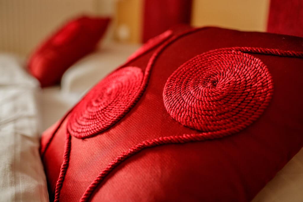Weiches rotes Kissen im Hotel Toscanina, ideal zum Wohlfühlen.