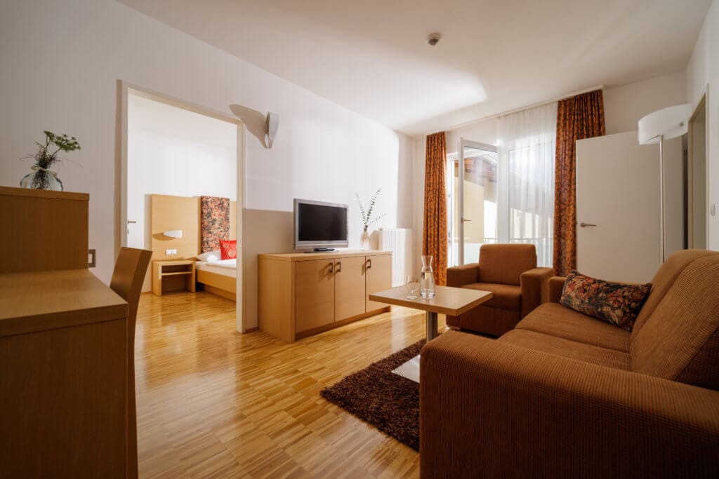 Moderne Junior-Suite im Toscanina mit Wohnzimmer, TV und Balkon sowie separatem Schlafzimmer (ohne Fernseher).