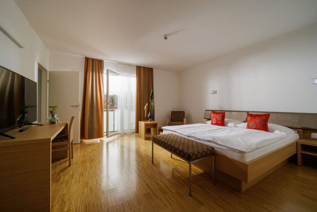 Geräumiges Hotelzimmer mit Balkon, modernem Interieur und Blick.
