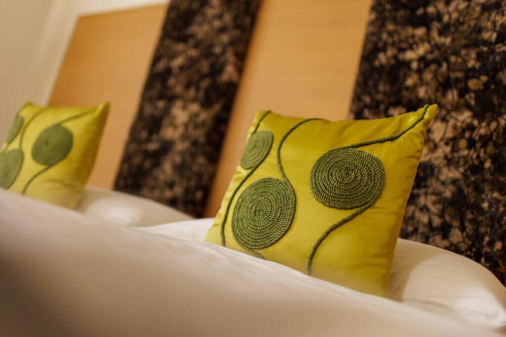 Komfortables Hotelzimmer mit grünem Dekokissen, ideal für Ihren Aufenthalt.