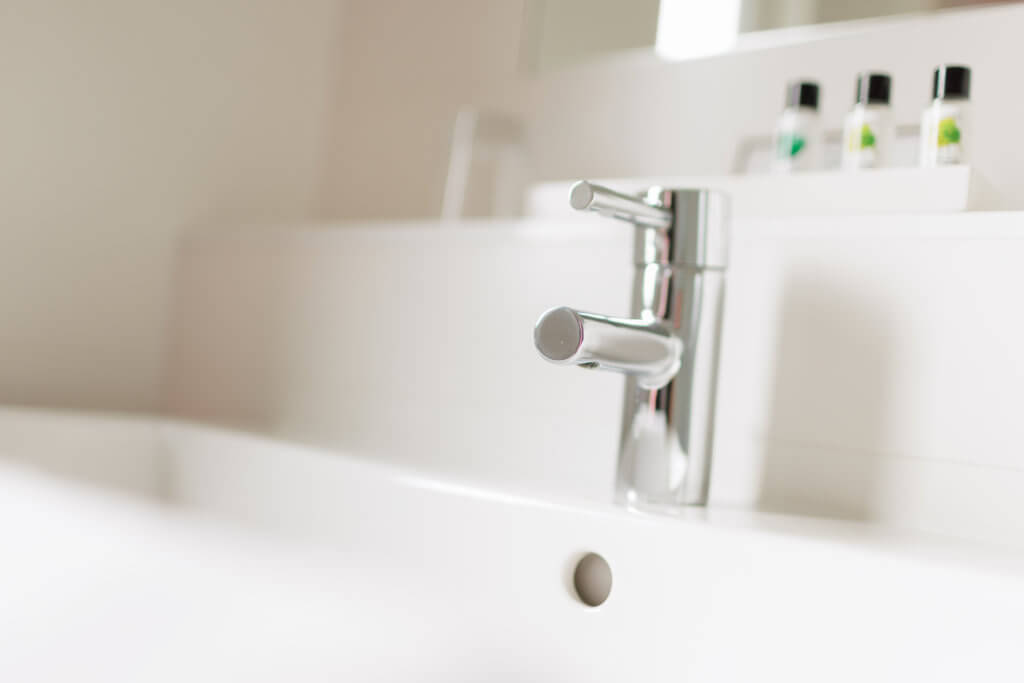 Modernes Badezimmer im Hotel Toscanina mit Waschbecken und Pflegeprodukten.