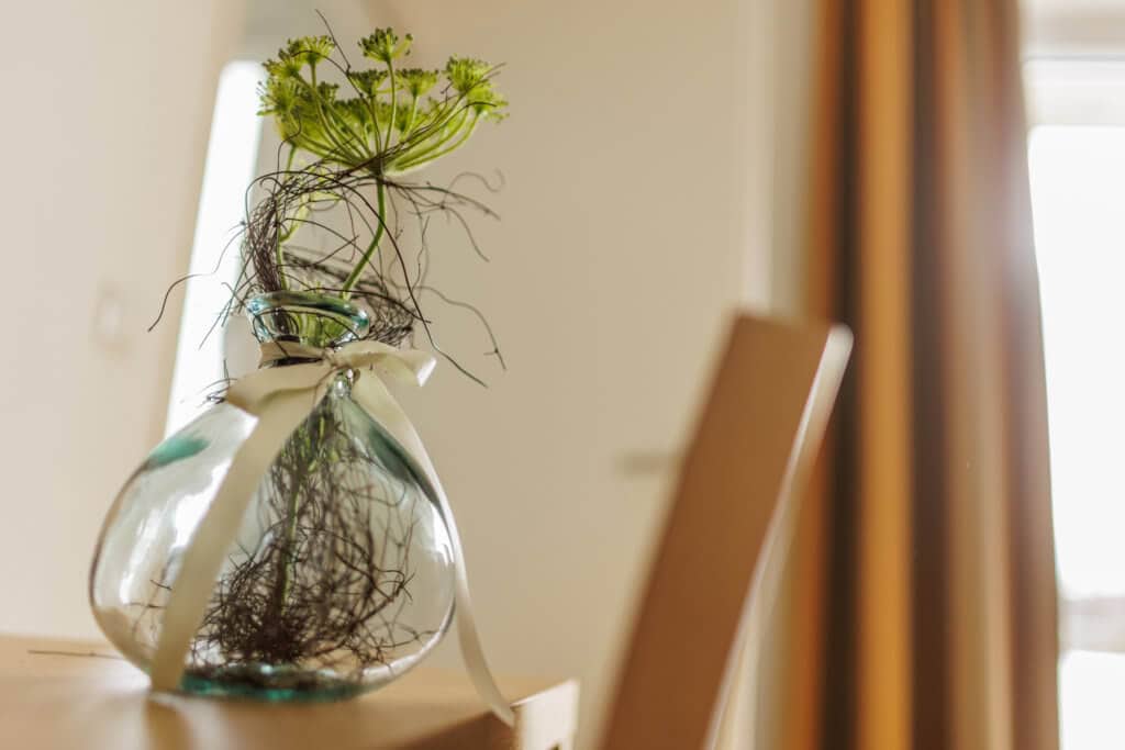 Blumen im Glas mit Wasser und dekorativem Band, stilvolle Raumdekoration.