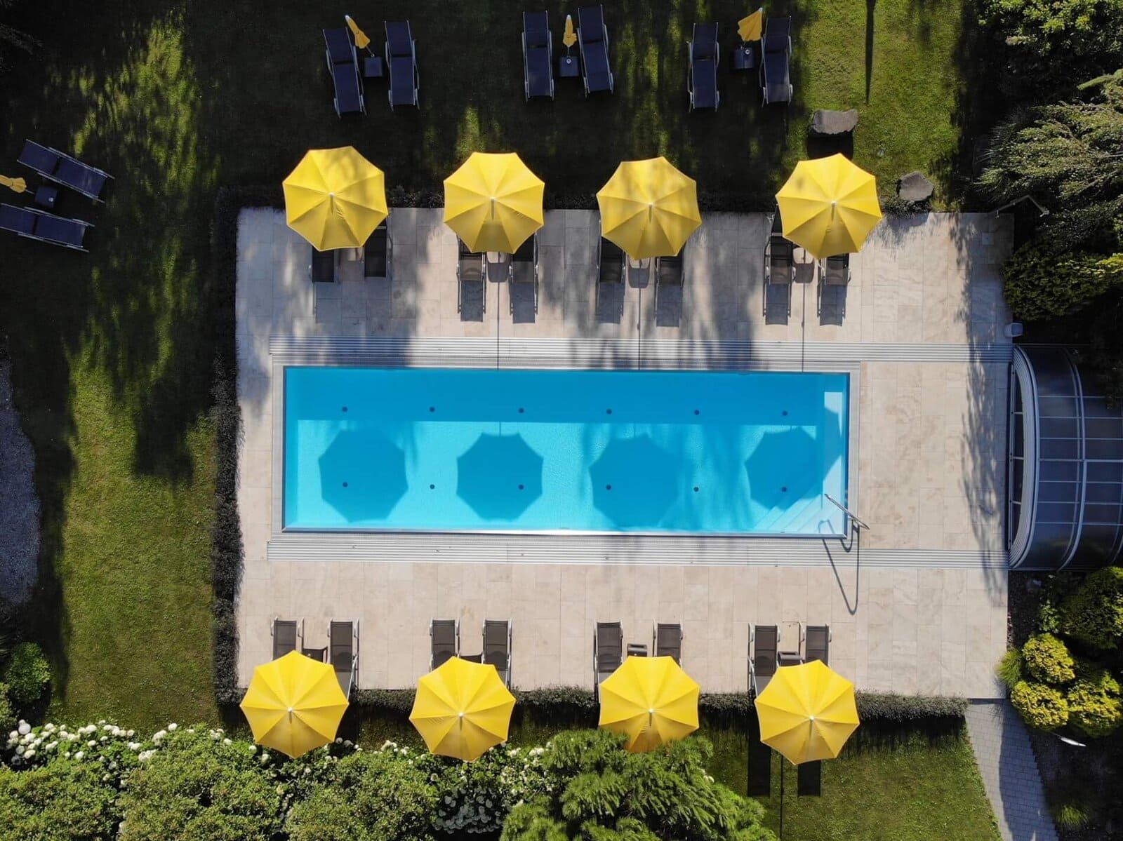 Pool mit Sonnenschirmen und Liegen im Hotel Toscanina, ideal für Sommerurlaub aus Vogelperspektive